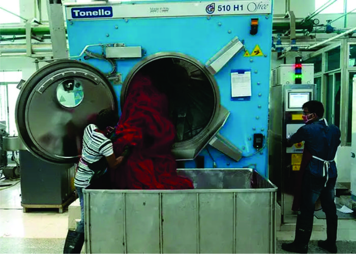 Industrial fabric washing machine with operators performing acid wash, stone wash, silicone softening, and specialty garment washes for premium finish and hand feel